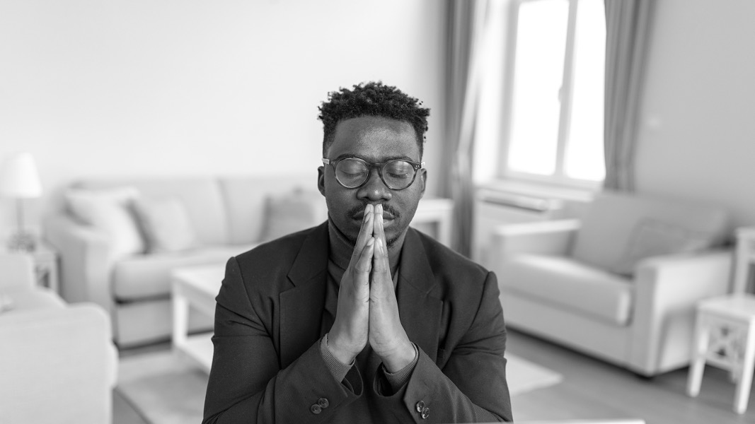 An image of a man praying at a desk