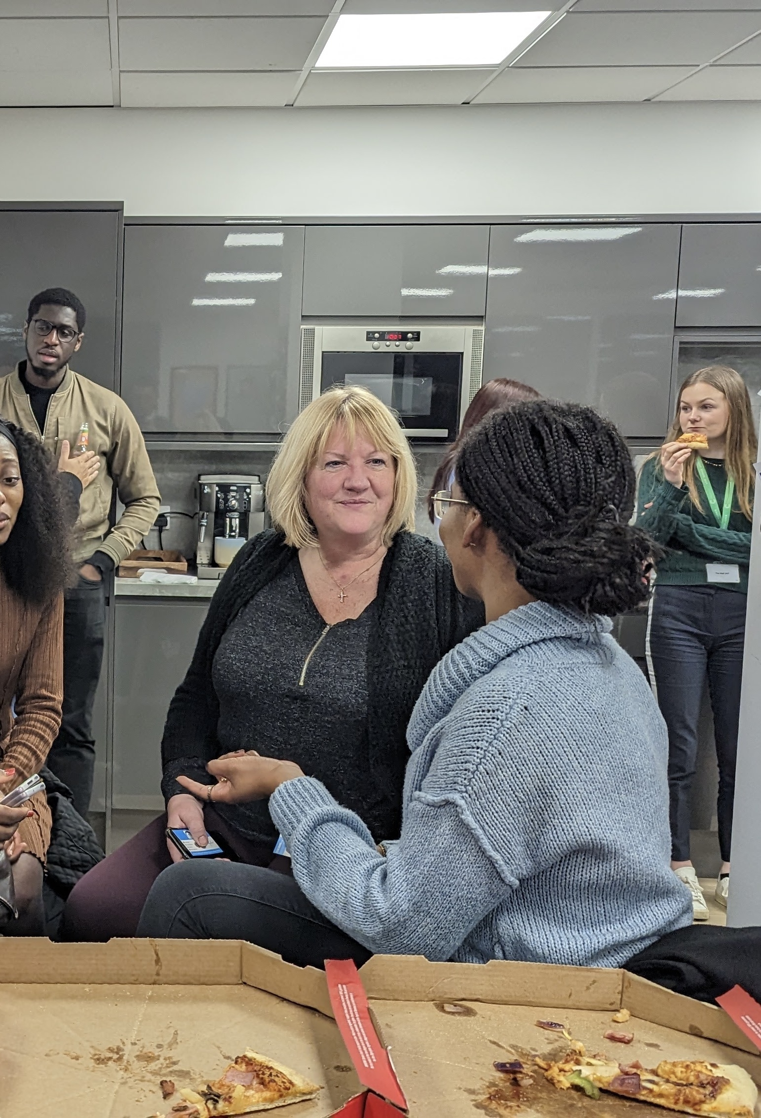 Women chatting and laughing over pizza at a gathering