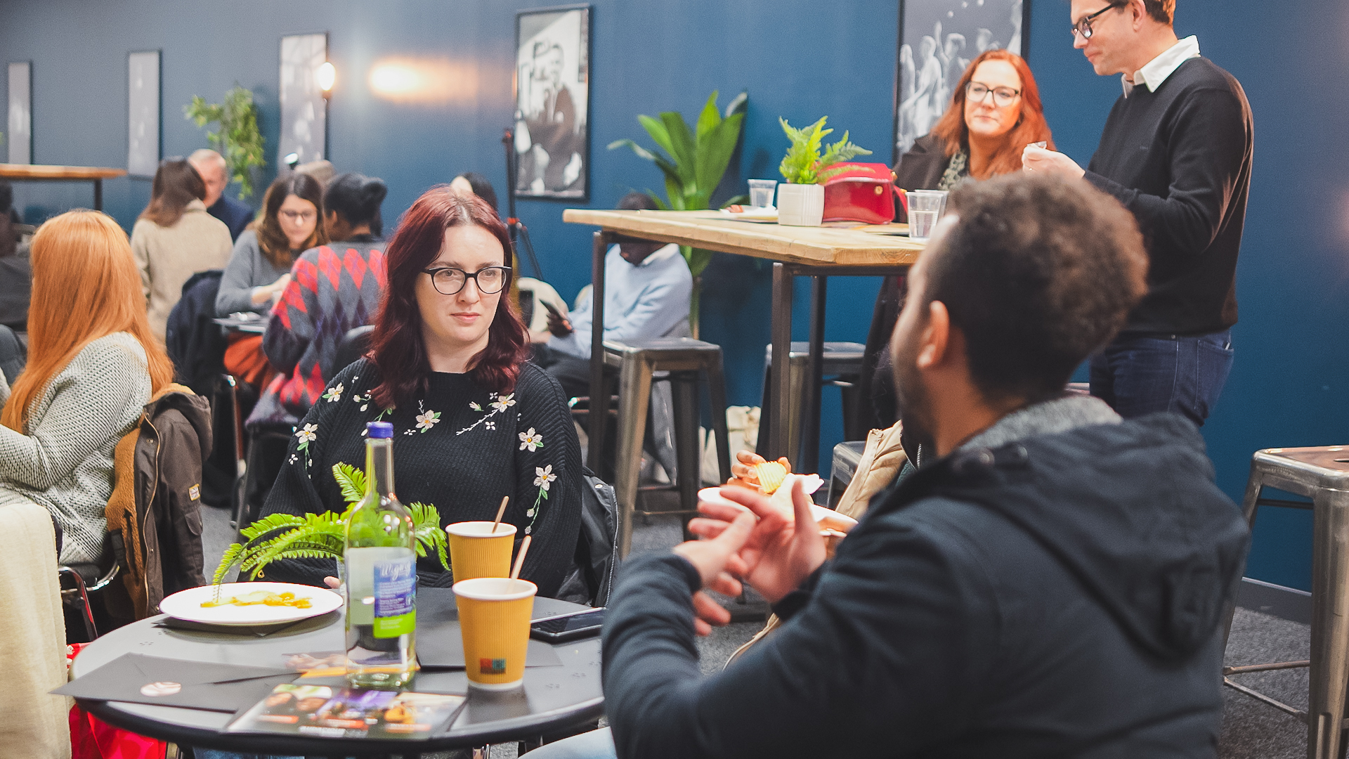 People chatting around café tables at an IGNITE! gathering